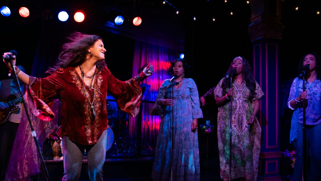 From the moment the band hits its first bluesy riff, the production establishes its mission: this is a celebration not only of Janis herself, but of the entire musical lineage that fueled her singular sound. The show smartly frames Joplin within the tradition of the blues and soul women who shaped her — voices like Bessie Smith, Nina Simone, Aretha Franklin, Etta James, and Odetta. These artists were not merely influences; they were the emotional architecture behind Janis’s explosive style. And by placing them center stage alongside her, the production reminds us that Joplin did not emerge from nowhere. She was the wildest flower in a very rich garden.